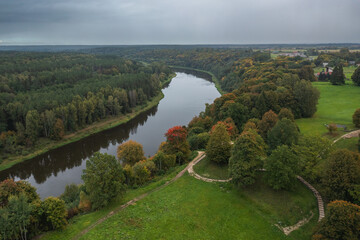 Fototapeta na wymiar Punia mound in Lithuania with green grass and autumn trees background, road to mountain