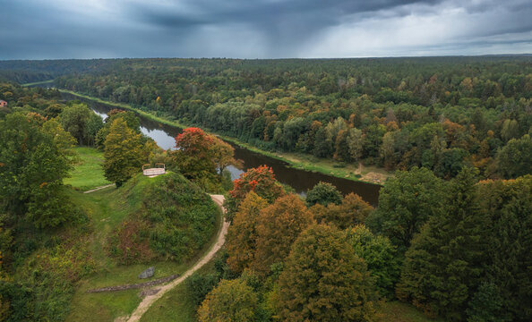 Punia mound in Lithuania with green grass and autumn trees background, road to mountain