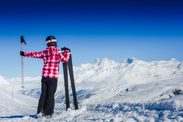 Happy female skier resting on top of the mountain observing nature at ski resort on a beautiful...