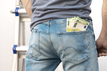 Male jeans butt with a few hundred euro notes in the trouser pocket.