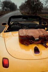 car on the road with vintage suitcase ready to travel