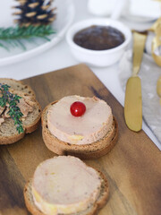 A slice of traditional fresh French foie gras on a wooden plate with thyme leaves and currant beside with  onion marmalade with a holidays decoration preparing for festive celebrate.
