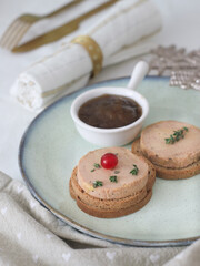 A slice of fresh traditional French foie gras in a plate with a holidays decoration on table with napkin, fork and spoon. Beside with onion marmalade. Preparation of festive celebration.