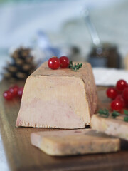 Close up of traditional of fresh French foie gras on a wooden plate with red currant and festive holidays decoration.It is a popular and well-known delicacy in French cuisine © Pkheawtasang
