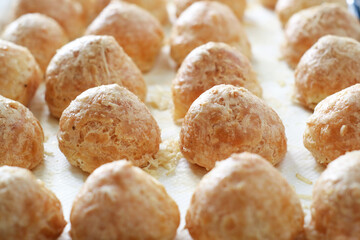Close up of row of cooked French Gougères. It's a traditional pastry made with savory choux dough. The pastry  know as typically of Burgundy region take as an appetizer. 