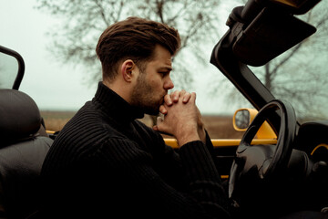 Man sitting in the car cabriolet on empty road 