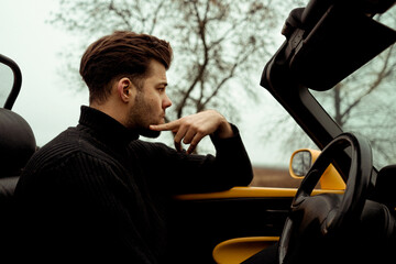 Man sitting in the car cabriolet on empty road 