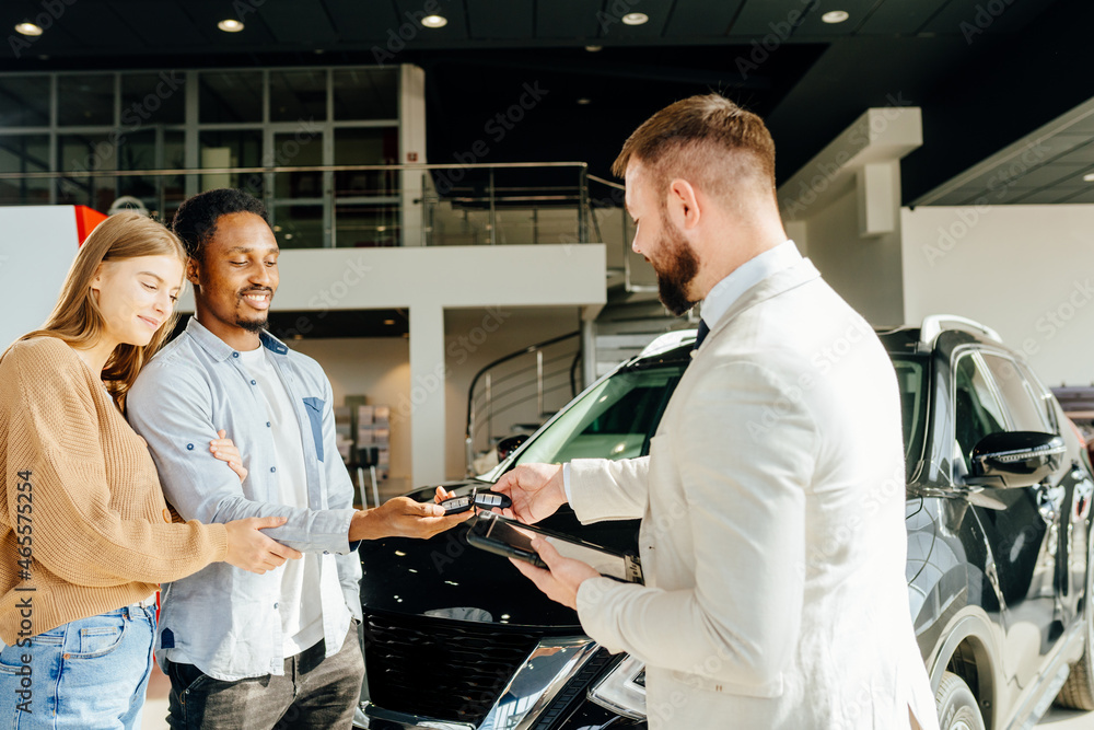 Sticker Salesman giving keys from new auto to multicultural couple