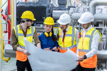 A portrait of an industrial engineer with blue print in a factory,working.Manager and engineer reviewing blueprints in steel factory.