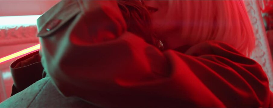 Close up shot of young romantic couple dancing close together and flirting under red neon light