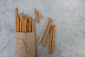 Bread sticks, with sesame seeds and whole grain flour on grey background. Top view, copy space.
