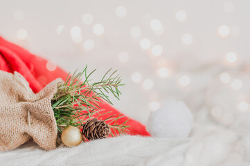 Santa Claus hat and Christmas tree branch over white background with lights and copy space