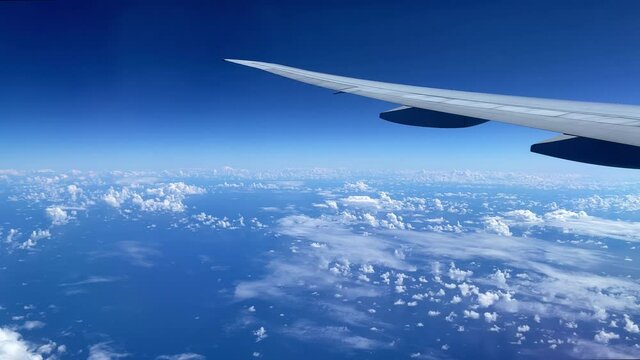 View from the illuminator to wing of the airplane to the ocean and clouds.