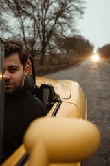 Man sitting in the car cabriolet on empty road 