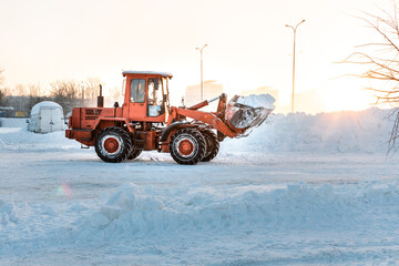 A bulldozer removes snow with a bucket after a blizzard. Cleaning snow drifts with a bulldozer. The...