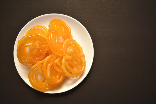 Selective focus picture of Indian Traditional Sweet called Jelebi kept in white plate in flat lay
