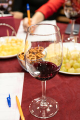 Naklejka premium red grape wine tasting - wineglass with portion on tested wine on table
