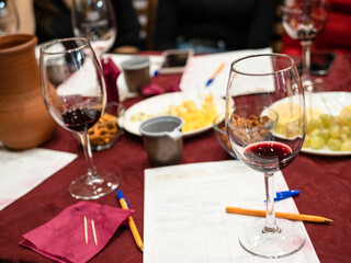 red grape wine tasting - wineglass with tested wine on notes on table