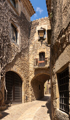 Naklejka premium narrow stone street with an arch in the medieval village of pals on a summer day