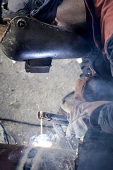 Construction worker arc welding the metal pipe.