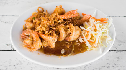 Delicious thai food, deep fried prawns in tamarind sauce on wooden table.
