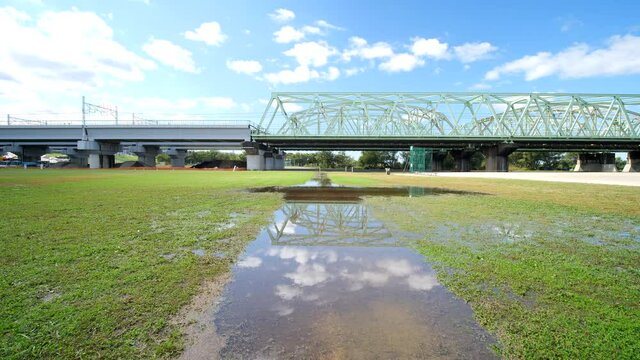 雨上がりの河川敷のグラウンドと鉄橋