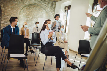 Speaker at business workshop and presentation. Audience with protective mask at the conference room.