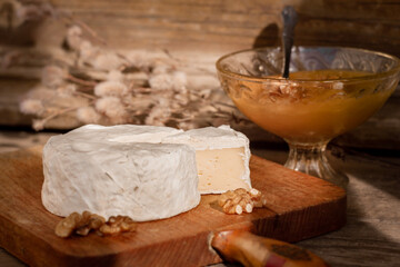 Camembert cheese, walnuts, sacking on cutting board, cut slice Camembert cheese, wooden background...