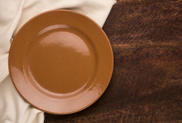 empty plate and a cloth napkin on a wooden background, top view with copy space for food photography