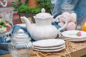 Banquet dessert table decorated with plates, cutlery, glasses, ceramic teapot and flower arrangements. Copy, empty space for text