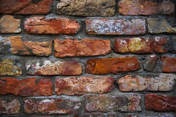 Grey white black red orange old vintage brick wall background. Rustic cemented dark brick house wall texture with grunge surface. Shabby Building Facade With Damaged Plaster. Aged weathered exterior