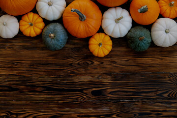 Bunch of pumpkins of different kinds, shapes and colors on wooden background as a symbol of autumnal holidays with a lot of copy space for text.