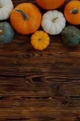 Bunch of pumpkins of different kinds, shapes and colors on wooden background as a symbol of autumnal holidays with a lot of copy space for text.