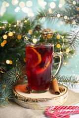 Christmas glasse of hot mulled red wine with oranges, clove, cinnamon and anise near gifts and decor. Christmas lights on background, cozy atmosphere, festive mood. Family time, new year eve.