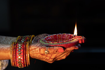 Beautiful Woman lady hand with bangles holding Handcrafted Eco Friendly Clay Diya Deep Dia Glowing lamps for Hindu festival Laxmi poojan (Diwali)