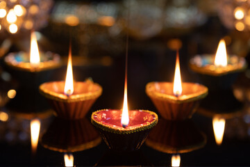 Eco Friendly Clay Diya Deep Dia Glowing lamps arranged on a reflective base Hindu festival Laxmi pooja (Diwali),with glittering background bokeh