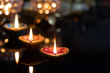 Eco Friendly Clay Diya Deep Dia Glowing lamps on a reflective base Hindu festival Laxmi pooja (Diwali),with glittering background bokeh