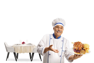 Cheerful chef smiling and holding a meat dish in front of a restaurant table