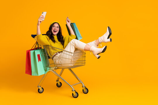 White excited woman taking selfie on cellphone in shopping cart