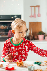 Handsome boy preparing cookies for christmas at home in pajamas