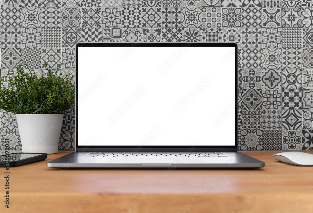 Poster laptop with blank screen on table in home interior with pattern tiles in the background