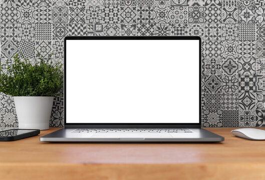 Laptop with blank screen on table in home interior with pattern tiles in the background