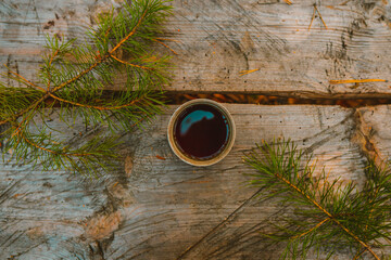 Mug with Coffee, Top View, on a Wooden Background Among the Christmas Tree Branches. Tea on the Table in the Park. Picnic in the Nature. Coffee Concept Photo.