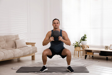 Muscular man training with kettlebell at home