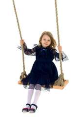 Lovely blonde little girl swinging on rope swing