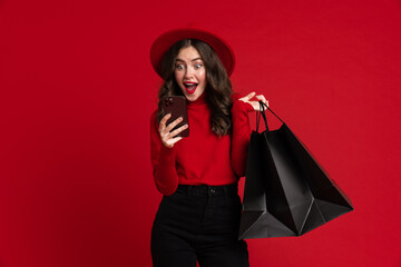 White woman laughing while posing with shopping bags and cellphone