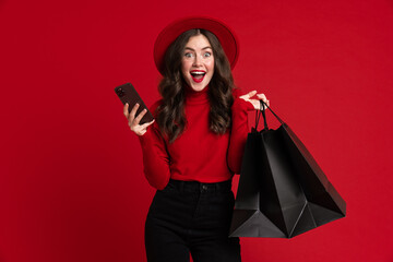 White woman laughing while posing with shopping bags and cellphone