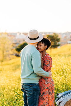 Romantic loving diverse couple cuddling in nature on sunny day
