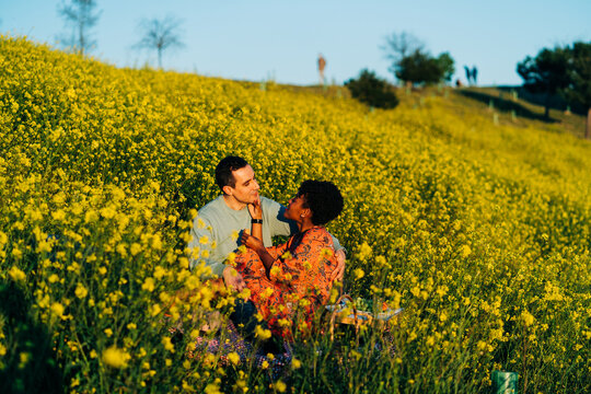 Tender diverse couple having picnic on field