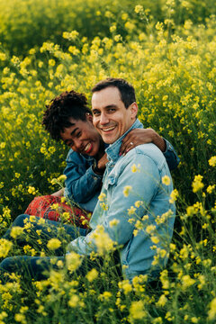 Happy young diverse couple looking at camera in meadow in sunlight